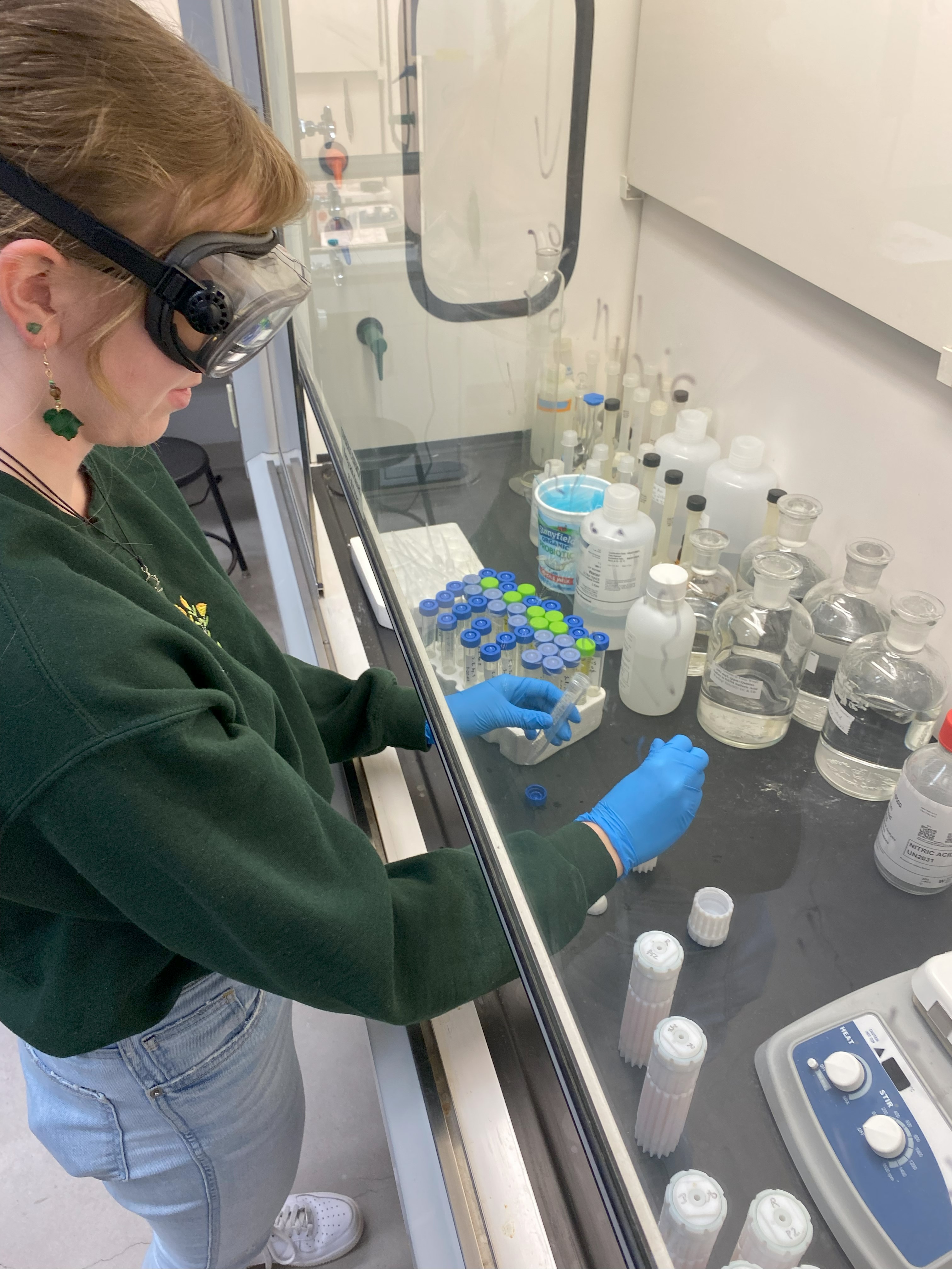 "Photo taken of NMU-ABL student research technician digesting food produce samples in trace metal grade nitric acid under a fume hood to prepare samples for heavy metal analysis using ICP-MS.